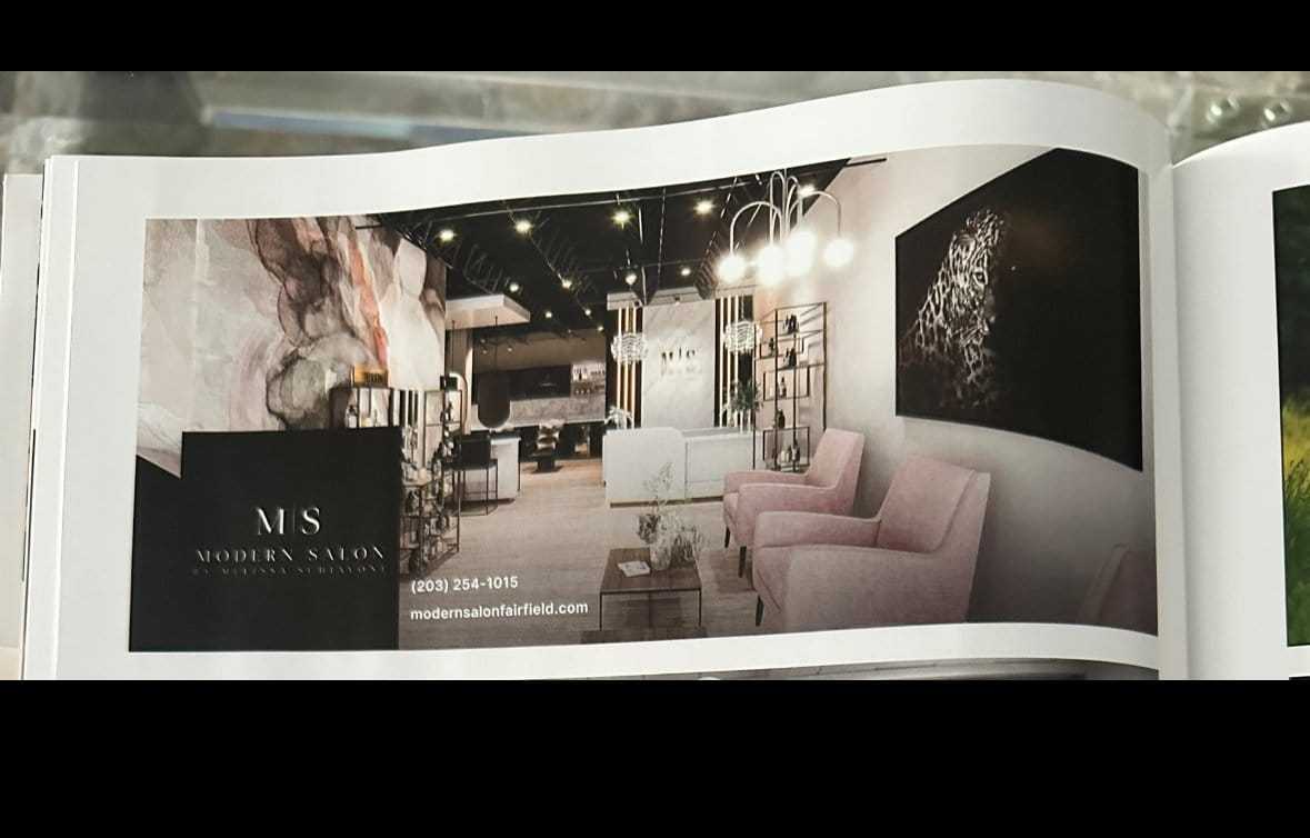 Modern salon interior with pink chairs, abstract art, and elegant lighting fixtures.