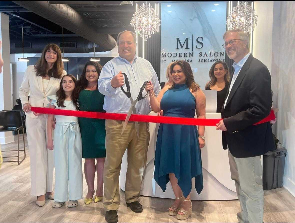 Ribbon-cutting at Modern Salon with a group of smiling people, including two holding scissors.