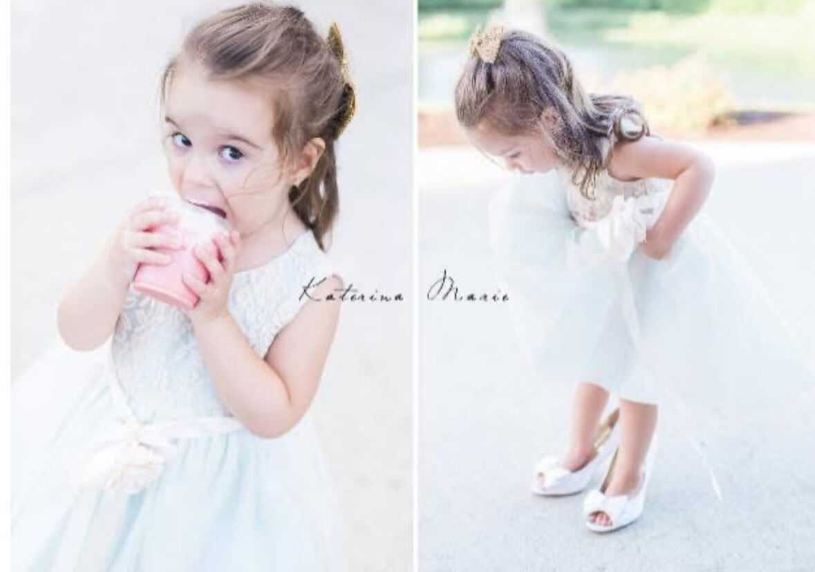 Little girl in a white dress enjoying a drink and looking at her shoes.