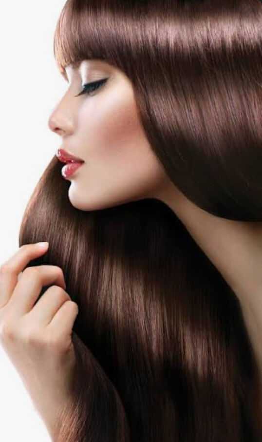 Woman with long, flowing brown hair gracefully touching her strands.