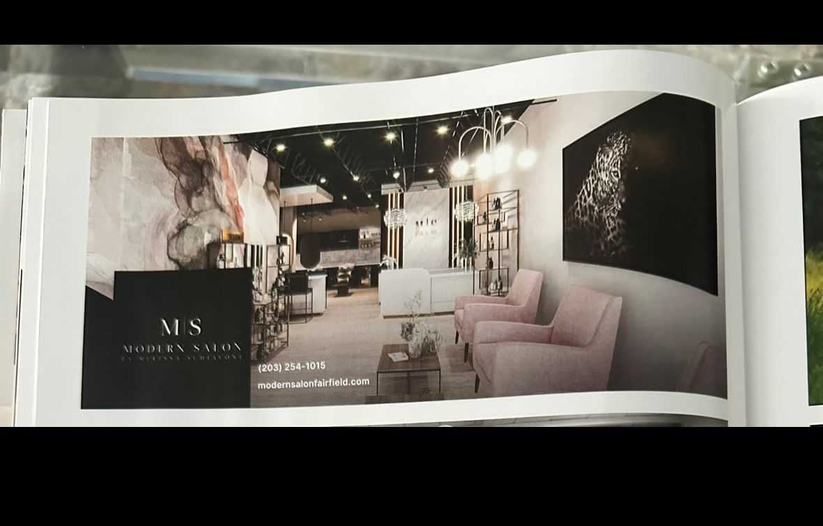 Modern salon interior with pink chairs, abstract art, and elegant lighting fixtures.